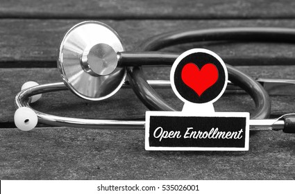 Open Enrollment word written on blackboard with Stethoscope on wooden background - Medical Concept                    