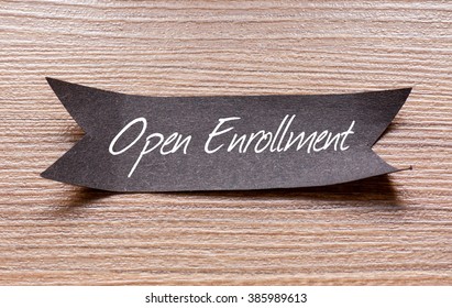 Open Enrollment words written on Black papper with wooden background