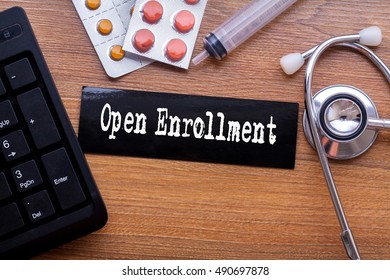 Open Enrollment words written on label tag with medicine,syringe,keyboard and stethoscope with wood background,Medical Concept