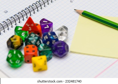 Open Exercise Book With Sticky Card, Pencil And Role Playing Dices - Stock Photo