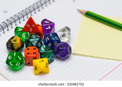 Open Exercise Book With Sticky Card, Pencil And Role Playing Dices - Stock Photo