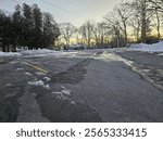 An open exit to a parking lot area with patches of ice stretching along it in places.