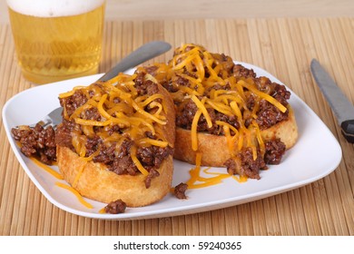 Open Face Sloppy Joe Sandwich On Texas Toast Covered With Shredded Cheese And A Drink In Background