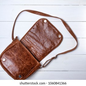 Open Female Brown Leather Bag On A White Wooden Background, Top View