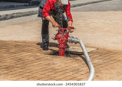 Open fire hydrant with a connected hose and splashing water.Water in motion.Blur