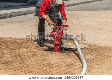 Open fire hydrant with a connected hose and splashing water.Water in motion.Blur