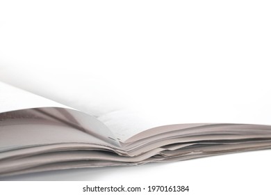 Open Folded Newspaper Lies On A White Table. Photographed From A Low Point Of View, Very Shallow Depth Of Field. Copy Space