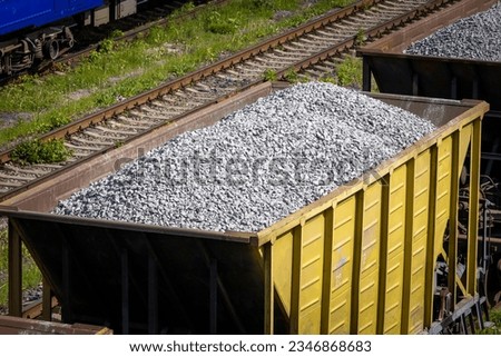 Open freight railway wagons loaded with crushed stone. Freight transportation of bulk building materials by rail. Shot from the top angle