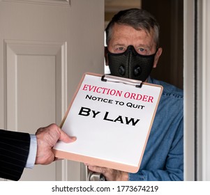 Open Front Door With Man In Suit Handing An Eviction Notice To A Defaulting Renter With Face Mask During Coronavirus Epidemic