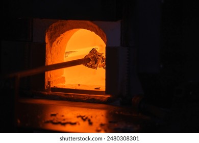 Open furnace of a glass blowing workshop with molten glass on a  blowpipe inside - Powered by Shutterstock