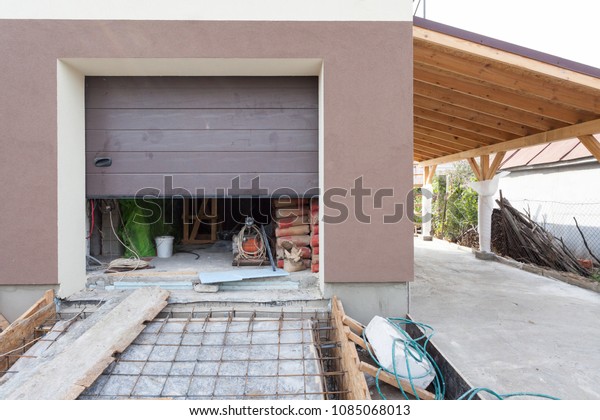 Open garage door in modern house with\
foundation under\
construction