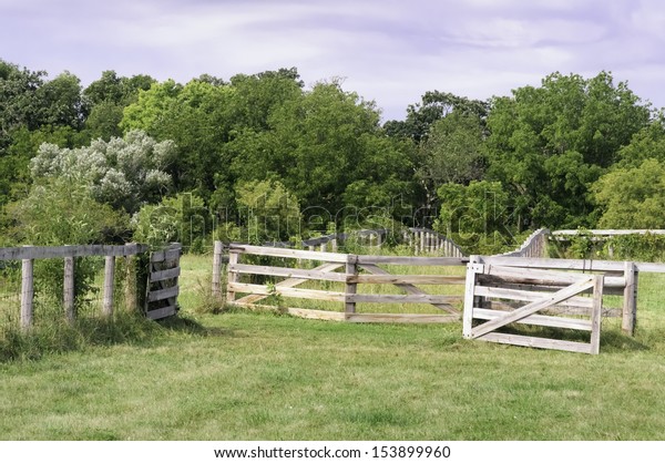 Open gate and fences of wood and\
wire mesh on Midwestern farm maintained for public\
education