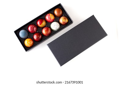 Open gift box with assortment of homemade chocolate bonbons. Modern hand painted chocolate candy. Product concept for chocolatier