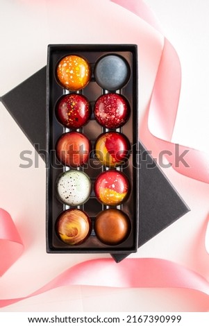 Open gift box with assortment of homemade chocolate bonbons. Modern hand painted chocolate candy. Product concept for chocolatier