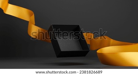 Open gift box flying with golden holiday ribbon on dark background. Black friday, christmas and new year shopping sale promo display. Premium product placement in empty present box design.