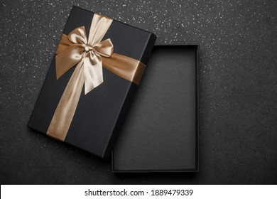 Open Gift On A Black Background. Gift Box With A Golden Ribbon. Place For An Inscription. Mockup