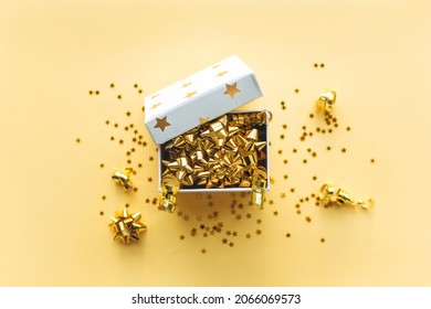 Open gift white box with tinsel and confetti on a gold background. Celebrating Christmas or New Years or winning a prize or a promotion or other holiday concept. Flat lay, top view