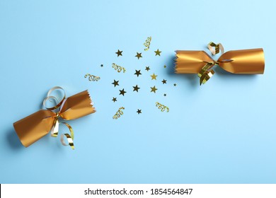 Open Golden Christmas Cracker With Shiny Confetti On Light Blue Background, Top View