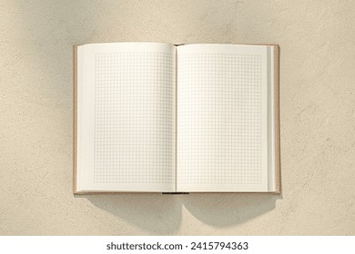 Open graph ruled composition or exercise book or notebook in sunlight on stone texture