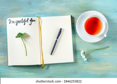 Open Gratitude Journal With A Pen And A Cup Of Tea, With The Handwritten Phrase I Am Grateful For And Some Plants