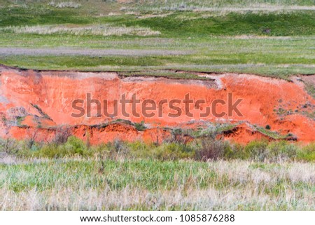 the open in the ground exposing the red Sandstone in the grass