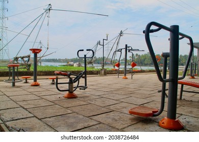 An Open Gymnasium In The Park Near The River With Fishing Nets In The Background