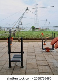 An Open Gymnasium In The Park Near The River With Fishing Nets In The Background