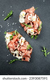 Open ham sandwiches, arugula and cream cheese. Appetizers on a dark background. top view. copy space for text.