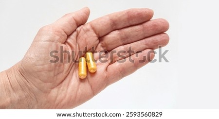 Open hand with two orange curcumin capsules