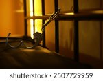 Open Handcuffs Hanging on Jail Cell Bars in Dim Light