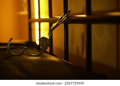 Open Handcuffs Hanging on Jail Cell Bars in Dim Light