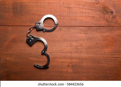 Open Handcuffs On A Wooden Table