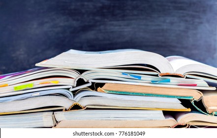 Open hardback and textbook stacked on the table on blackboard background. The concept of intelligence comes from education. focused on the textbook. - Shutterstock ID 776181049