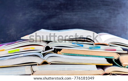 Open hardback and textbook stacked on the table on blackboard background. The concept of intelligence comes from education. focused on the textbook.