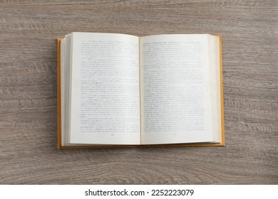 Open hardcover book on wooden table, top view