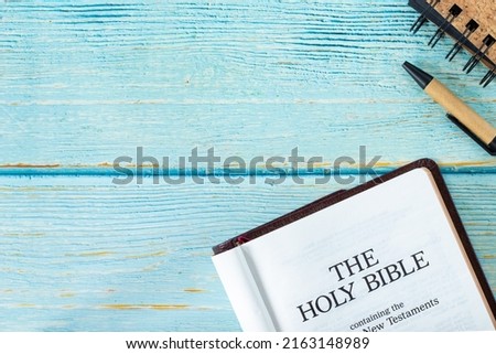 Open Holy Bible Book on a wooden table background with a pen and notebook. Copy space. Top view. Flat lay. Studying old and new testament Scriptures by God Jesus Christ. Christian biblical concept.