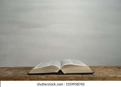 Open Holy Bible on a old wooden table and white wall background. Religion concept. - Shutterstock ID 1559958743