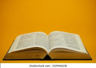 Open Holy Bible  on a yellow background table. Religion concept.