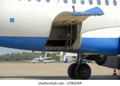 Open Hydraulically Operated Cargo Compartment Door Of An Airplane At The Airport