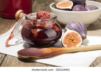 Open jar of figs pickled in port  wine, fruit, cooking spoon and bottle on rustic wooden table - Powered by Shutterstock