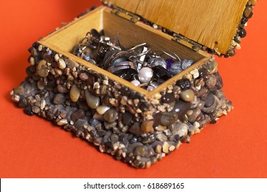 Open jewelry box made from wood and jackstone, orange background