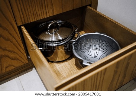 Open kitchen drawer with cookware including pots and colander ideal for home organization cooking lifestyle and functional kitchen design