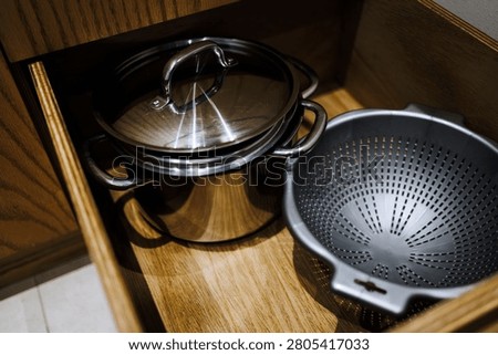 Open kitchen drawer with cookware including pots and colander ideal for home organization cooking lifestyle and functional kitchen design