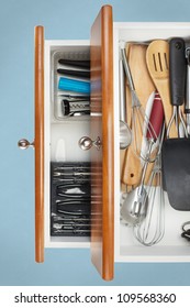Open Kitchen Drawer with utensils on display with light blue background