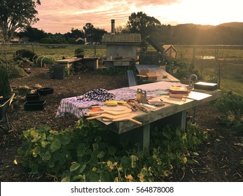 Open Kitchen With Old School Pizza Oven With Chimney And Outdoor Long Dining Table At Backyard Garden With Nature And Mountain View Background And Morning Light In The Country Town