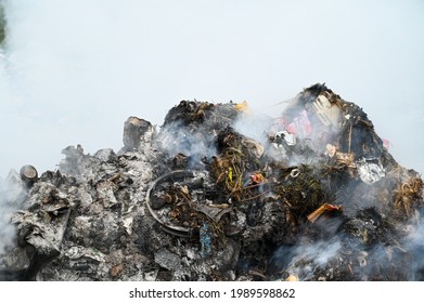 Open landfill site with burning waste. Burning pile of illegal garbage dump near city. The smoke and smell of the landfill area pollute the air. Air and environmental pollution.