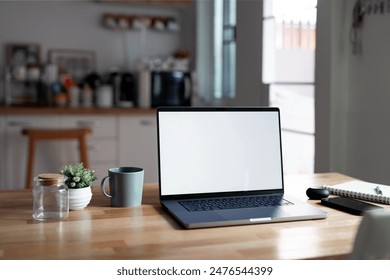 Open laptop with blank screen on a wooden desk in a kitchen room home office