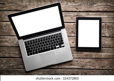 Open laptop with digital tablet. With isolated screen on old wooden desk.
