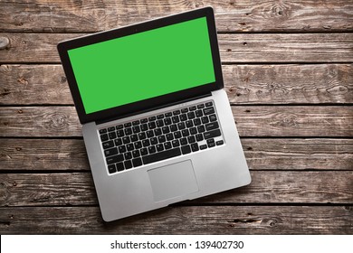 Open laptop with isolated green screen on old wooden desk. - Powered by Shutterstock