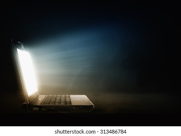 Open Laptop With Light Coming From Screen On Dark Background